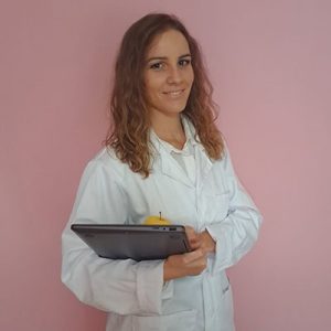 Médica con bata blanca y tablet en fondo rosa en Málaga.
