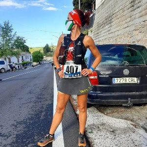 Corredora en carrera de montaña en Málaga con equipo deportivo y casco.